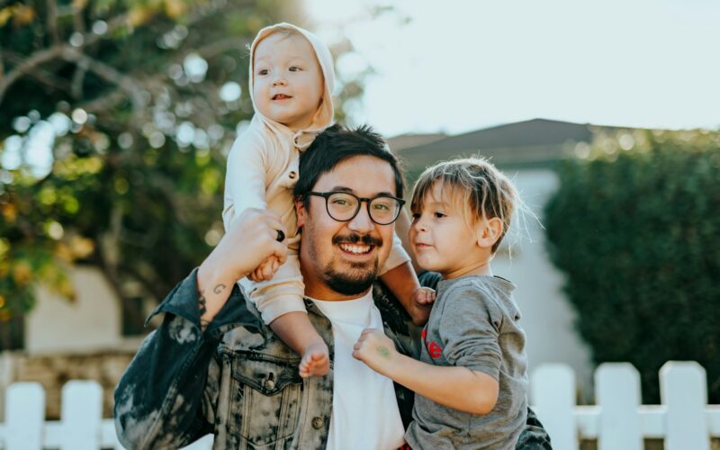 Dad smiles while holding two kids