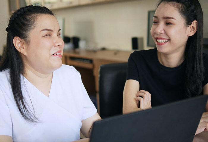 Happy Asian women co-workers in workplace including person with disabilities