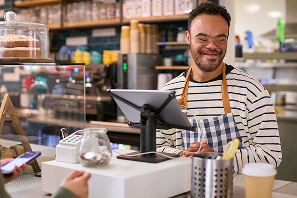 Man with Down Syndrome serving customer at coffee shop checkout