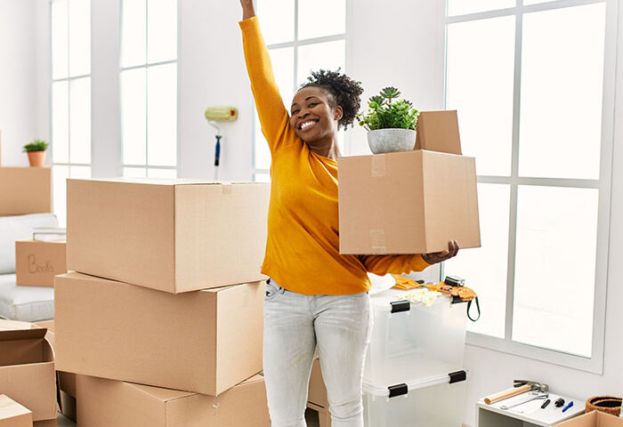 African american woman holding package as she unpacks into new house