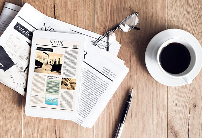 Newspaper with tablet on woodden table with coffee