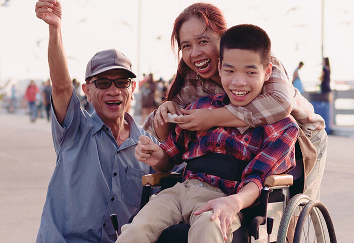 Asian Disabled child in wheelchair and parents at the beach ​